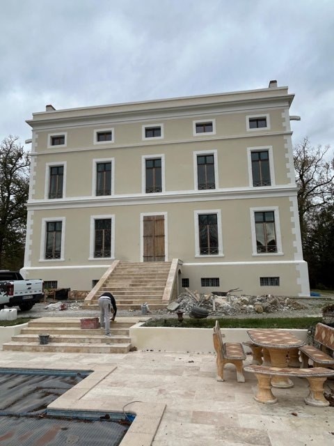 Façade côté jardin de la demeure rénovée, avec escalier en pierre et terrasse