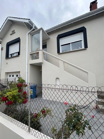 Maison individuelle à la façade enduite claire avec encadrements de fenêtres anthracite